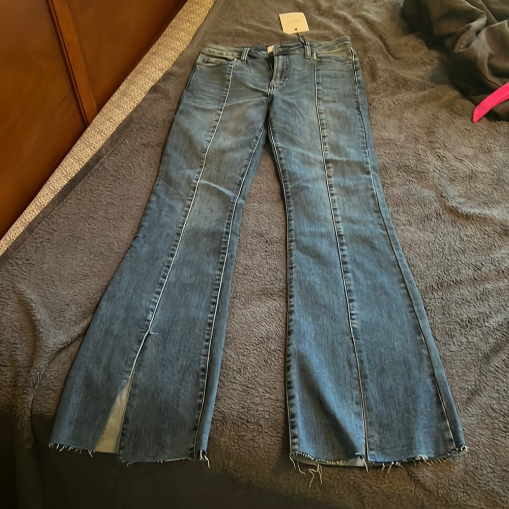 Flare jeans with frayed him, and has a split in the front of the leg